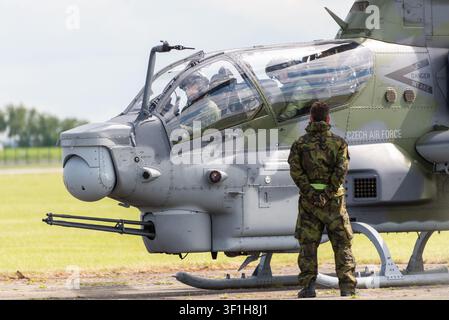 Tschechischer Armeesoldat steht neben einem Bell AH-1Z Viper-Kampfhubschrauber auf einem Grasflugplatz während einer militärischen Luftshow Stockfoto