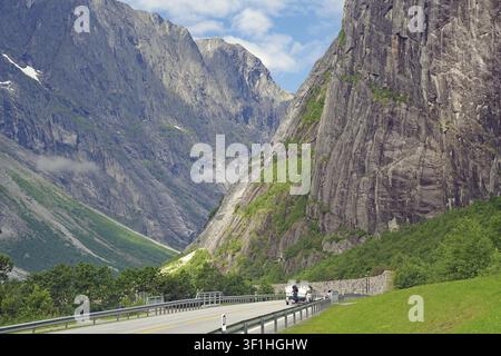 Motorradfahrer auf einer einsamen Bergstraße, flankiert von steilen Klippen und grünen Bergen unter einem blauen Himmel, Drehort von Tom Cruise, Raumadalen, Trollv Stockfoto