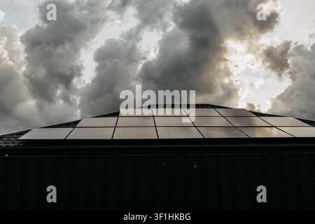 Dachsolarmodule auf einem modernen Wohnhaus unter dramatischen Gewitterwolken, die erneuerbare Energien und nachhaltiges Li veranschaulichen Stockfoto