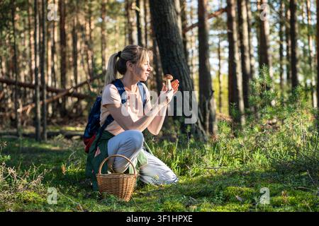 Glückliche Frau, die Pilze im Wald sammelt, hält den hochgeschätzten Steinpilz in den Händen Stockfoto