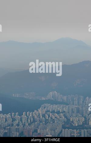 Dichte Apartment-Bebauung in Seoul, umgeben von geschichteten Bergketten unter einem dunstigen Himmel Stockfoto