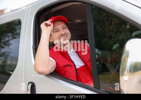 Kurier in Uniform fährt Auto. Lieferdienst Stockfoto