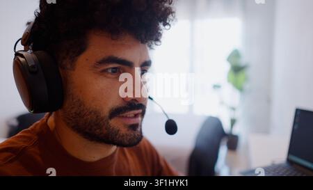 Mitarbeiter, der von zu Hause aus in einem Online-Meeting arbeitet, mit Headset Stockfoto