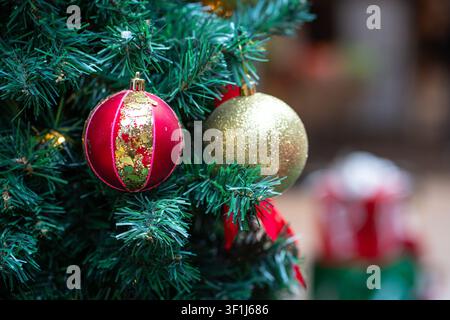 Weihnachtskugeln hängen an einem Baum mit Geschenken oder Präsenten im Hintergrund. Stockfoto