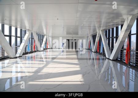 Eine Weitwinkelaufnahme eines hellen und luftigen Korridors in einem modernen Hochhaus. Der Boden ist mit poliertem Weißmarmor mit grauen Maserungen versehen, der das Licht reflektiert Stockfoto