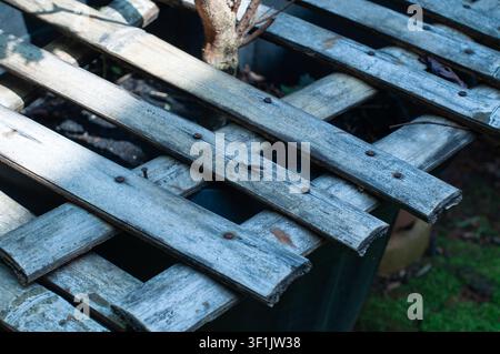 Eine Nahaufnahme eines rustikalen Bambusgitters, das einen Blumentopf in einem Hausgarten abdeckt. Die Bambusstreifen sind in einem Rastermuster angeordnet und miteinander gebunden. Stockfoto