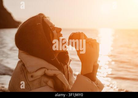 Frau Apfel Strand Profil einer jungen Frau, die spielerisch einen Apfel an der Küste bei Sonnenuntergang leckt, während sie Natur und Gesundheit genießt Stockfoto