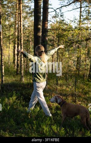 Aktiver Lebensstil, Körperpflege und Bewegung, positive Frau wandert im Wald begleitet von einem Hund. Stockfoto