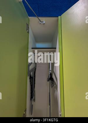 Ein Blick in einen hellgrünen Schließfach mit hängenden Kleiderbügeln und einer blauen Deckenplatte, gelegen im Hallenbad Bornheim in Frankfurt, Ge Stockfoto