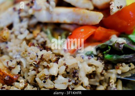 Ein lebendiger und gesunder Quinoa-Salat mit gegrilltem Hähnchen, saftigen Tomaten, knackigem Salat und einem cremigen Dressing. Stockfoto