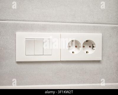 Die Verkabelungsinstallation zeigt Schalter neben elektrischen Steckdosen an einer Wand zur Steuerung der Stromversorgung in einem häuslichen Umfeld. Stockfoto