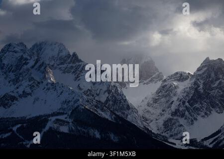 Schneebedeckte Berggipfel unter dramatischen Sturmwolken Stockfoto