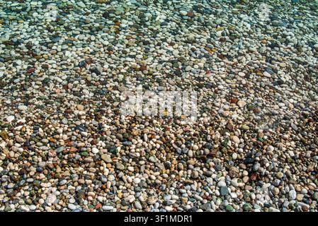 Mittelmeer-Kieseln mit trockenen, nassen und unter Wasser liegenden Steinen in kristallklarem Wasser, Antalya, Türkei Stockfoto