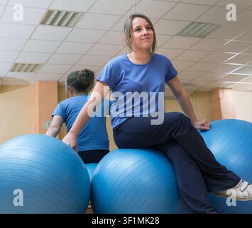 Porträt einer glücklichen jungen Frau, die auf Fitnessbällen im Fitnessstudio sitzt Stockfoto