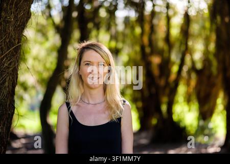 Junge blonde Frau lächelt im Naturwaldporträt Stockfoto