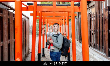 Ein Vater und ein Kind genießen einen Tag am Horikoshi-Schrein in Osaka, Japan, umgeben von lebhaften roten Torii-Toren. Diese ruhige Kulisse fängt einen Moment des Cu Stockfoto