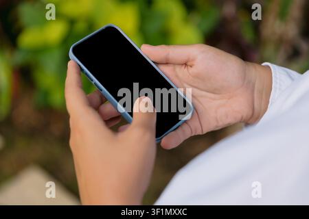 Nahaufnahme eines Smartphones in der Hand mit leerem Bildschirm im Freien Stockfoto