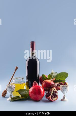 Rosh-Hashanah-Feier mit traditionellen Symbolen wie Wein, Äpfeln, Granatäpfeln, Honig und silbernen Bechern. Die koscheren Lebensmittel symbolisieren Süße Stockfoto
