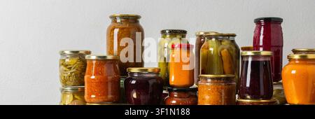 Canning ist eine häufige Aktivität in der Küche, da die Theke mit Gemüse und Obst gefüllte Gläser säumen. Diese Praxis hilft dabei, Lebensmittel für den Gewinn zu bewahren Stockfoto