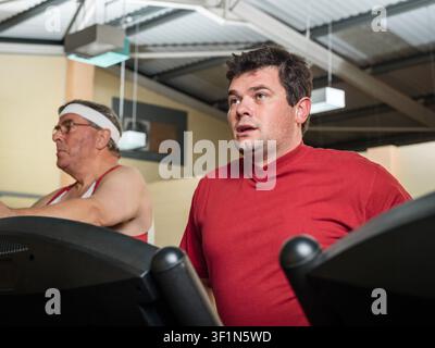 zwei Männer trainieren auf einem Laufband im Fitnessstudio Stockfoto