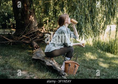 Frau trinkt aus einem wiederverwendbaren Becher im Freien, genießt einfache Momente, erfrischende Pause, langsames Leben, Flucht in die Natur Stockfoto