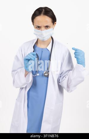 Professionelle Ärztin mit Schutzmaske hält eine Spritze im Studio Stockfoto