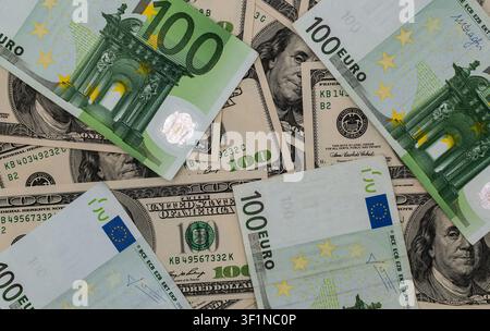 Verstreute Hundert-Euro- und US-Dollar-Banknoten als Hintergrund Stockfoto