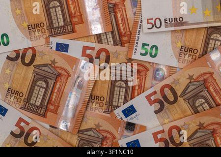 Nahaufnahme mehrerer 50-Euro-Banknoten, die in einem überlappenden Muster angeordnet sind und einen detaillierten finanziellen Hintergrund bilden. Stockfoto