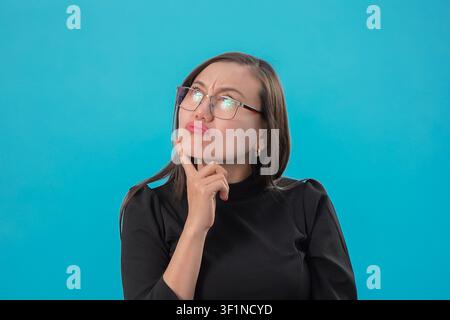 Frau denkt mit der Hand am Kinn im Studio Stockfoto