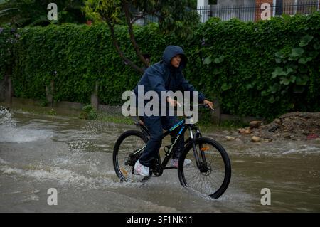 Lalitpur, Nepal. 13. Juli 2026. LALITPUR, NEPAL - 13. JULI 2026: Menschen schieben und fahren ihre Fahrzeuge durch eine überflutete Straße, nachdem starke Monsunregen Teile von Lalitpur im Kathmandu-Tal, Nepal, am 13. Juli 2026 überschwemmt haben. Die saisonalen Regenfälle verursachten lokale Überschwemmungen, die den Verkehr und das tägliche Leben in der Region störten. Foto von Sunil Pradhan/JNA Press/Sipa USA Credit: Sipa USA/Alamy Live News Stockfoto