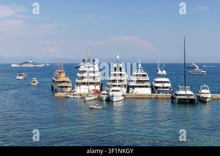 Korfu, Griechenland, 10. Juli 2026: Zahlreiche Luxusyachten und Boote liegen in einer belebten Bucht unter einem klaren blauen Himmel vor Anker Stockfoto