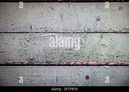 Alte Holzbretter mit rissiger salbeigrüner Farbe und kleinen roten Farbflecken, rustikale verwitterte Textur Stockfoto