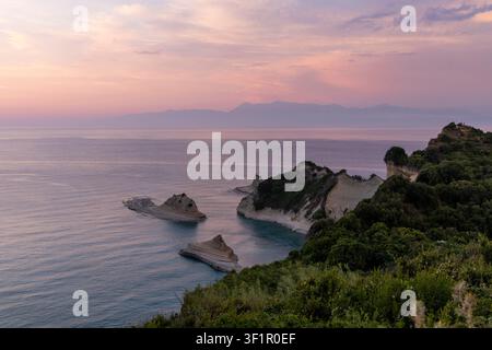 Klippen von Cape Drastis und einzigartige Felsformationen bei Sonnenuntergang, ruhige Gewässer der Ionischen See und üppige grüne Vegetation Stockfoto