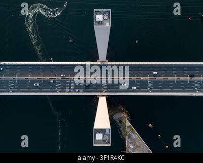 Luftbild der Bolte-Brücke mit Autos, die über die mehrspurige Autobahn fahren, und einem Boot, das unterhalb in Docklands, Victoria, Australien eine Spur im Wasser hinterlässt Stockfoto