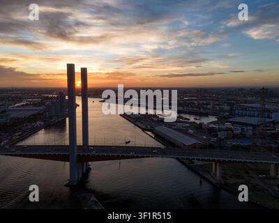 Luftbild der Bolte-Brücke, die den Yarra-Fluss bei Sonnenuntergang überspannt, mit dem Industriehafen und der Stadt Skyline im Hintergrund in Docklands, Victoria, Aus Stockfoto