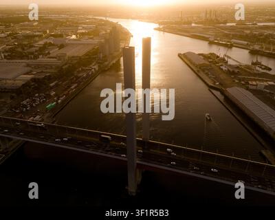 Luftaufnahme der Bolte-Brücke bei Sonnenuntergang mit Verkehr, der über den Yarra River im Industriehafengebiet von Docklands, Victoria, Australien, fährt. Stockfoto