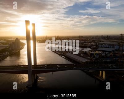 Luftaufnahme der Bolte-Brücke, die den Yarra-Fluss bei Sonnenuntergang überspannt, mit dem Industriehafen und der Stadtsilhouette im Hintergrund, Docklands, Victo Stockfoto