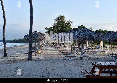 Trinidad, Kuba – Juli 2026: Reihe von Strohdächern und leeren Sonnenliegen entlang des Sandstrands im Hotelresort Melia Trinidad Peninsula. Stockfoto