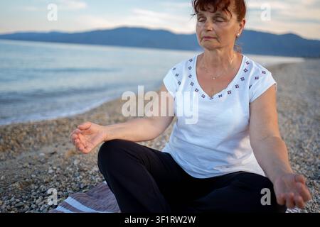 Ältere Frau beim Yoga am Strand Stockfoto