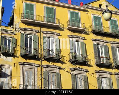 Verfallenes altes Gebäude mit gelber Fassade und grünen Holzläden in Neapel (Italien) Stockfoto