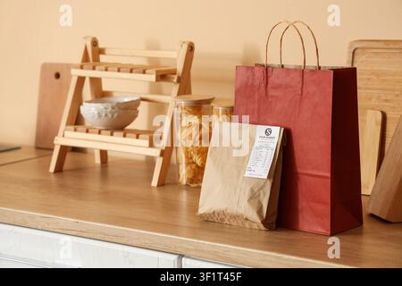 Lebensmittelmarkt-Lieferung mit rotem Papiertüte und brauner Papiertüte auf einer hölzernen Küchentheke, die Tüten enthalten Artikel von einem Lebensmittelmarkt, Online-Sho Stockfoto