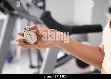 Frau hand hält eine Stoppuhr in einem Fitnessstudio, Fitnesstraining und Workout-Timing-Konzept, Bewegung und gesunder Lebensstil Stockfoto