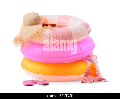 Stapel bunter aufblasbarer Schwimmringe mit einem Strohhut, einer Sonnenbrille, Flip-Flops und Sonnencreme für den Sommerurlaub Stockfoto