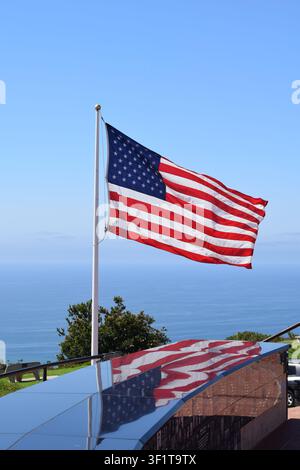 Amerikanische Flagge weht an einer Fahnenstange und spiegelt sich auf schwarzem Granit am Mt Soledad National Veterans Memorial in San Diego wider Stockfoto