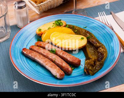 Gegrillte Würstchen mit Kartoffeln, Pfeffer und Kräutern Stockfoto