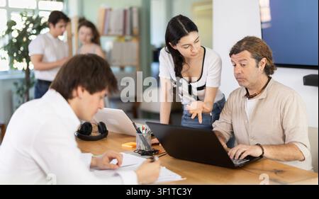 Mitarbeiter, die im Büro mit Laptops und Papierdokumenten arbeiten Stockfoto