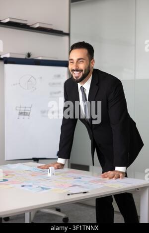 Geschäftsmann steht an einem Konferenztisch mit Verkaufsstatistiken in Diagrammen Stockfoto