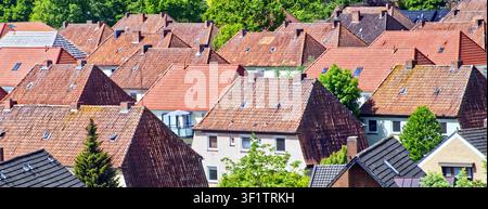 Luftaufnahme von vielen Häusern mit orangefarbenen Ziegeldächern und grünen Bäumen, die eine dichte WohngebietsSzene bilden Stockfoto