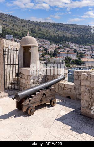 Dubrovnik, Kroatien - 27. Juni 2023: Stadtmauern mit Verteidigungsturm und Kanone, die die mittelalterliche Stadt an der Adria umgeben. Blick auf den Alten Hafen Stockfoto