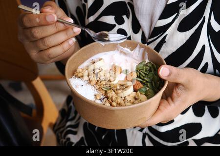 Genießt eine Schüssel Joghurt mit Früchten und Nüssen in einem Café Stockfoto